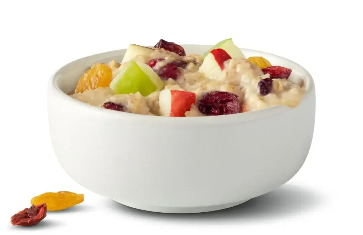 Bowl of oatmeal topped with fresh apples and dried fruit.